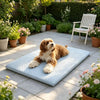A golden doodle dog relaxing on a light blue, quilted ice silk cooling pet mat outdoors.