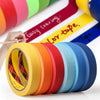 Rolls of orange multi-surface masking tape in various colors laid out on a white surface.