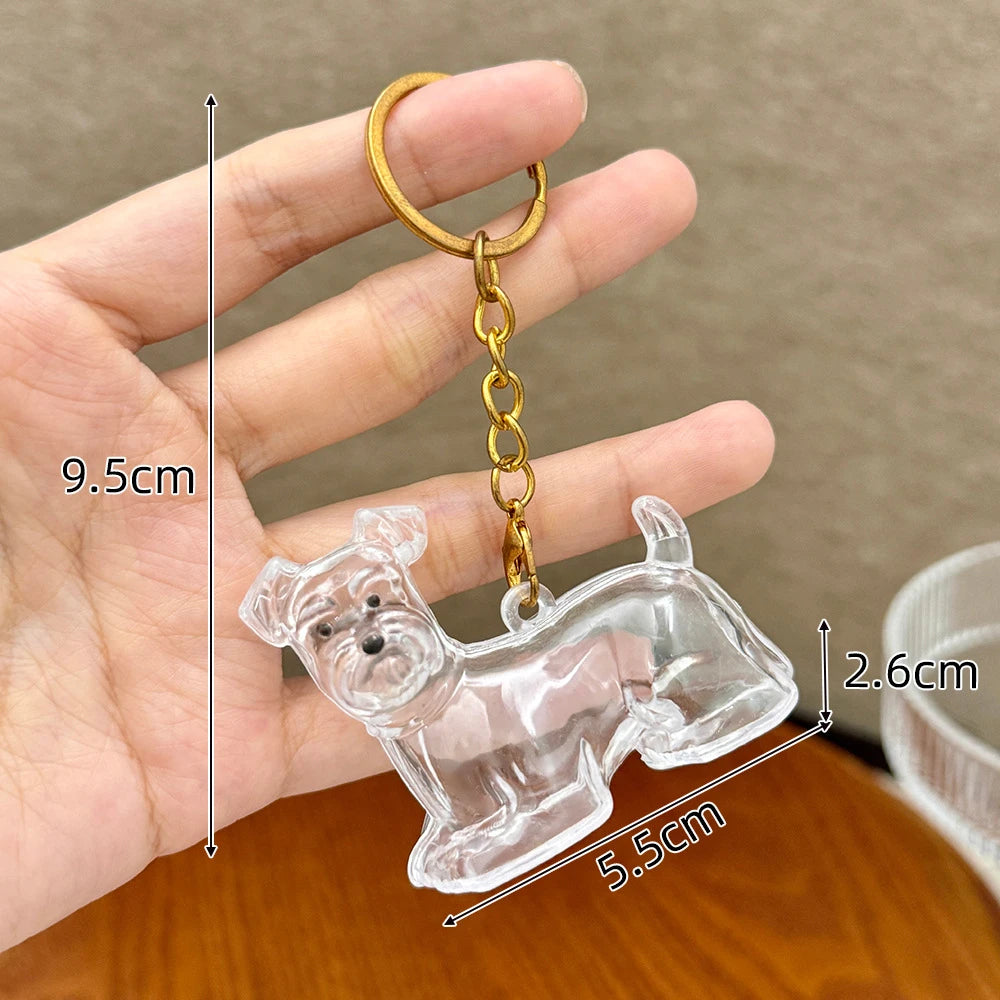 A clear, puppy-shaped pet hair keepsake keychain is held in a hand, showing its size and detail.