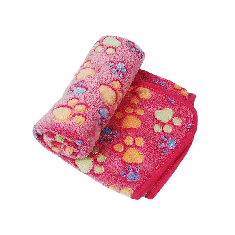 Rosa Korallen-Fleece-Haustierdecke, aufgerollt und ausgebreitet, mit bunten Pfotenabdruck-Mustern.