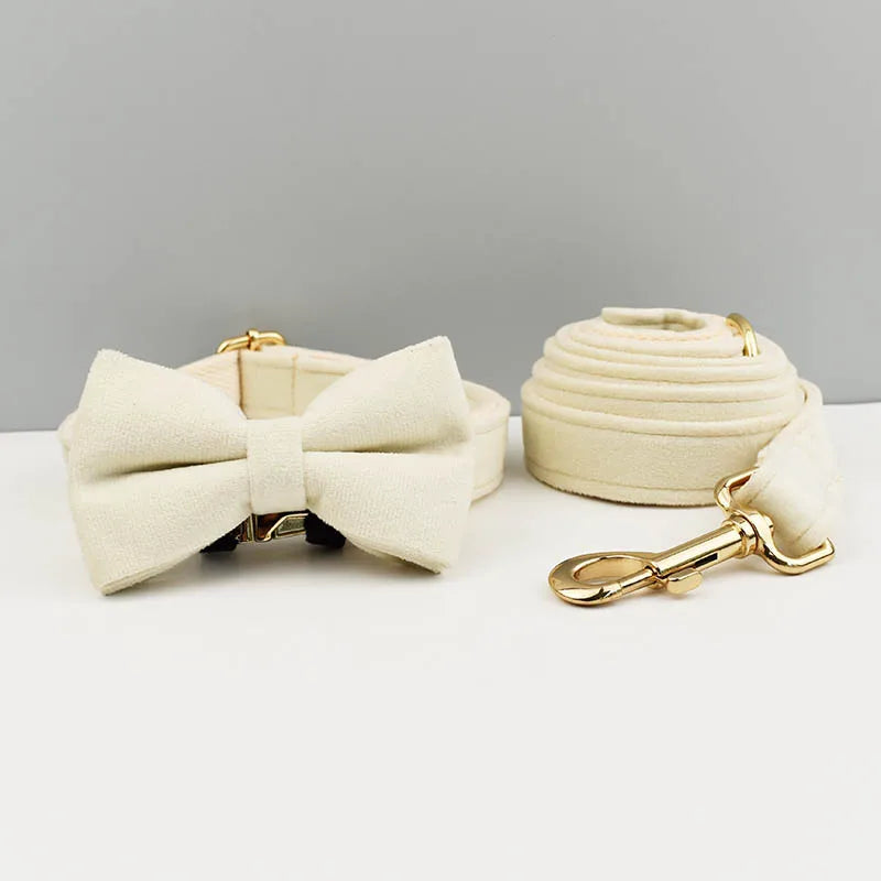 A cream-colored velvet dog collar and matching leash set with a bow tie displayed on a white surface.