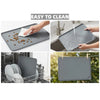 A gray silicone pet feeding mat being washed under running water, demonstrating its easy to clean feature.