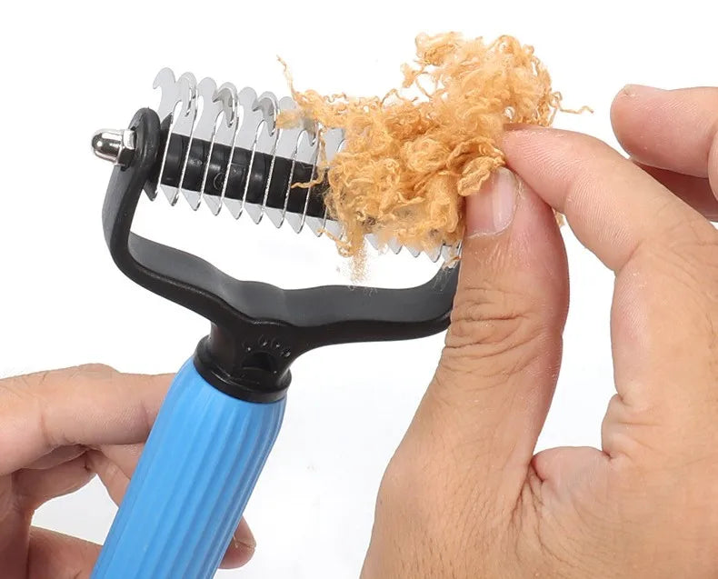 A hand holds a black comb with a blue handle, showing light brown dog hair being removed.