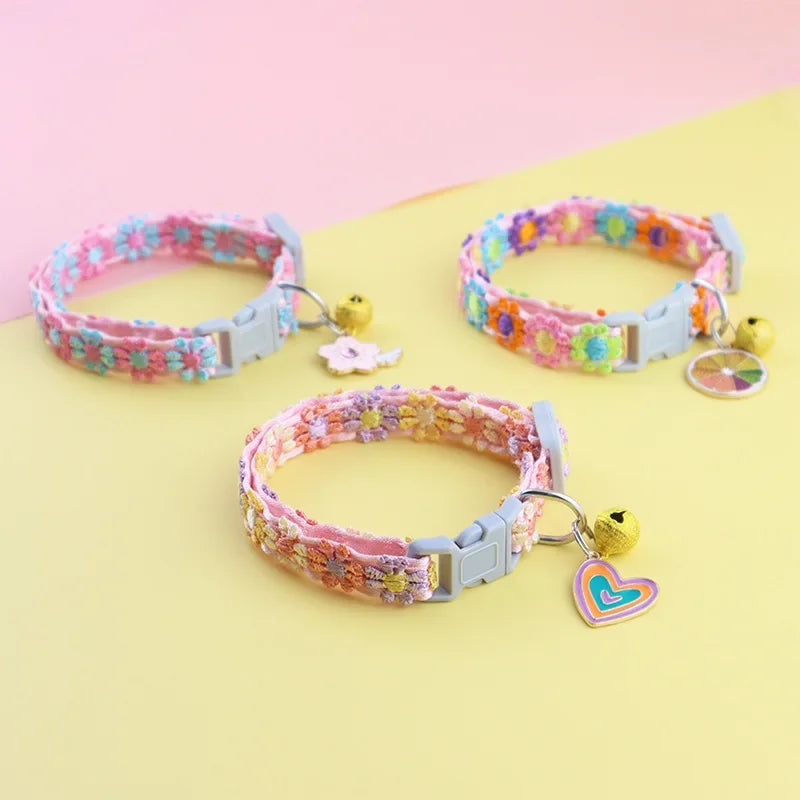 Pink and purple embroidered safety cat collar with a gold bell displayed on a light yellow background.