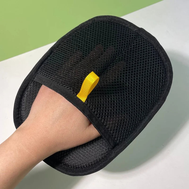 A hand wearing a black pet hair removal glove for cats and dogs, showing the textured mesh material.
