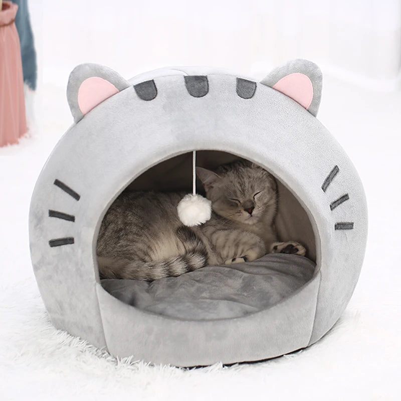 Lit de grotte pour chat gris avec ouvertures d'oreille et coussin réversible, avec un chaton endormi à l'intérieur.
