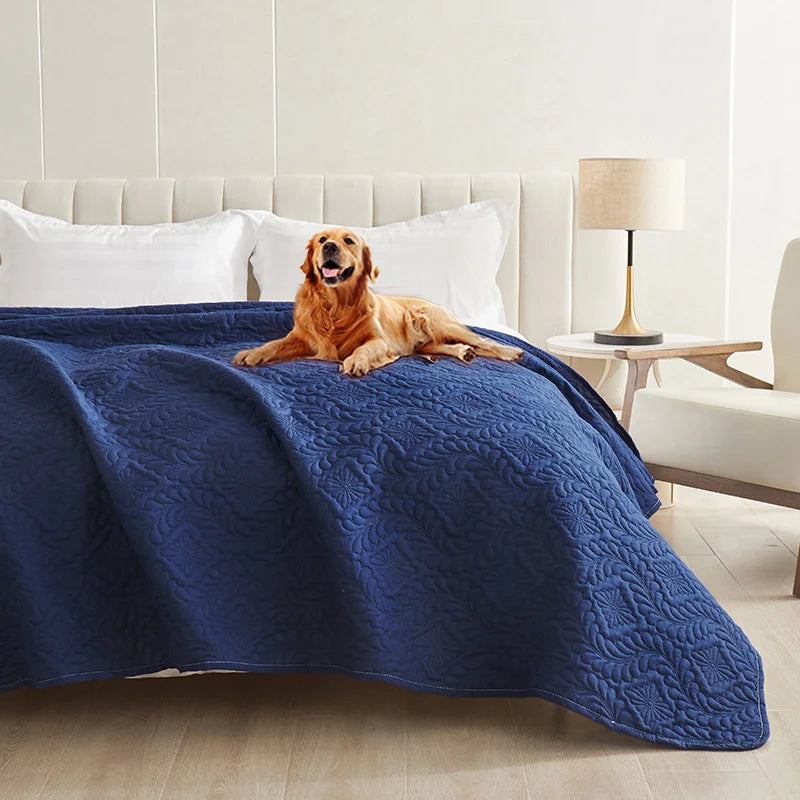 A golden retriever lies on a dark blue waterproof pet bed cover on a white sofa or mattress.
