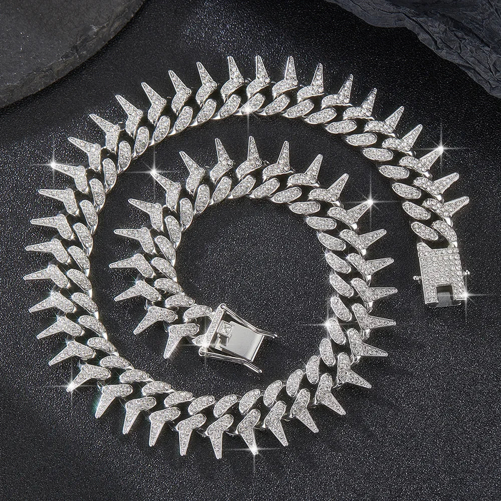 A silver spiked Cuban chain bracelet with diamond accents coiled on a dark surface.