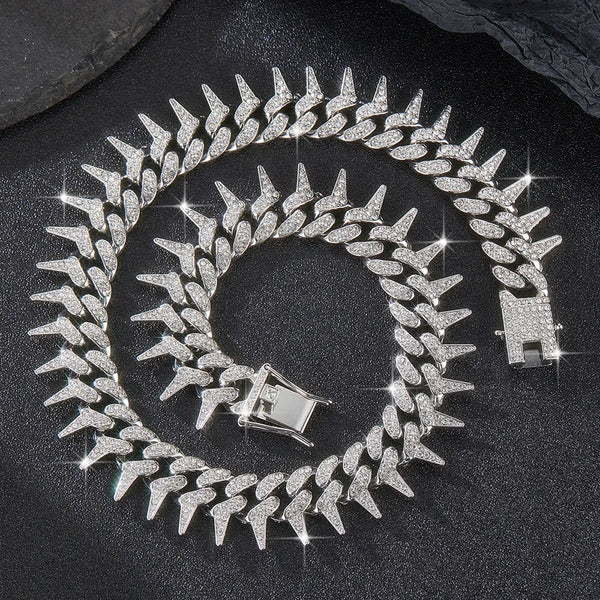 A silver spiked Cuban chain bracelet with diamond accents coiled on a dark surface.