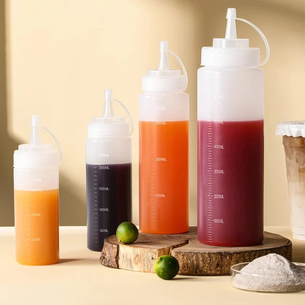 Un juego de botellas de condimentos exprimibles con líquidos de varios colores, incluyendo naranja y rojo, exhibidos sobre un