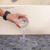 Una mano vierte agua de un vaso en una alfombra para pañales desechables para mascotas.