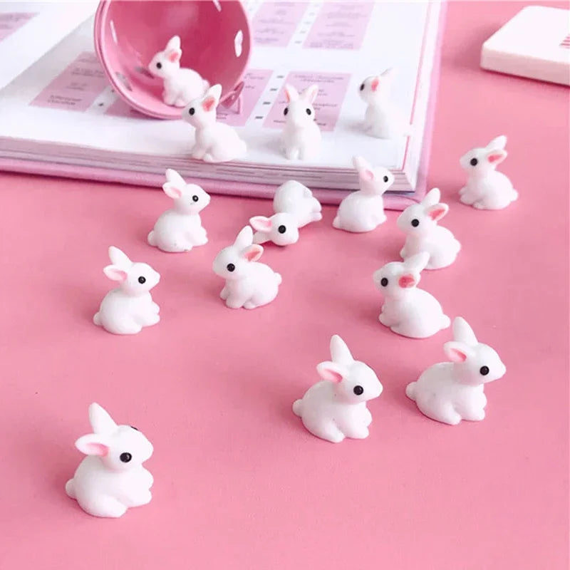 A collection of twenty white resin bunny figurines arranged on a pink surface.