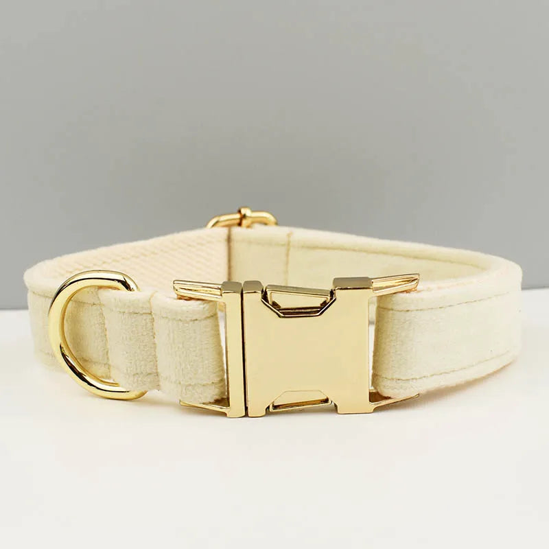 A cream-colored velvet adjustable dog collar and matching leash set with a gold bow tie buckle.
