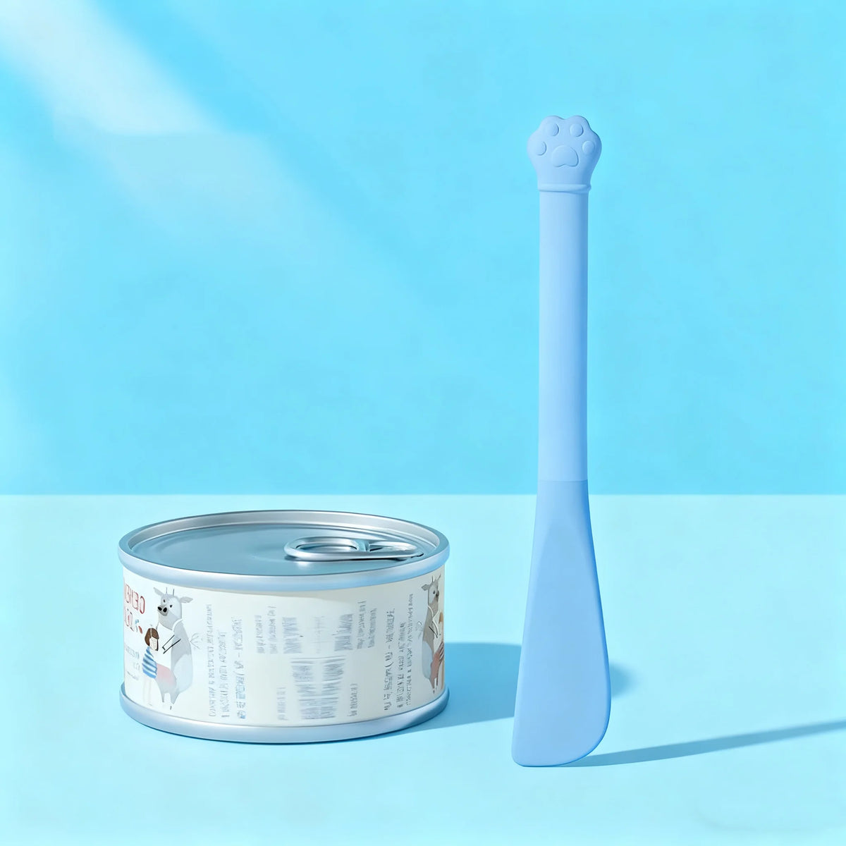 A light blue multi-purpose pet feeding spoon with a built-in can opener and seal cap is shown next to its metal container.