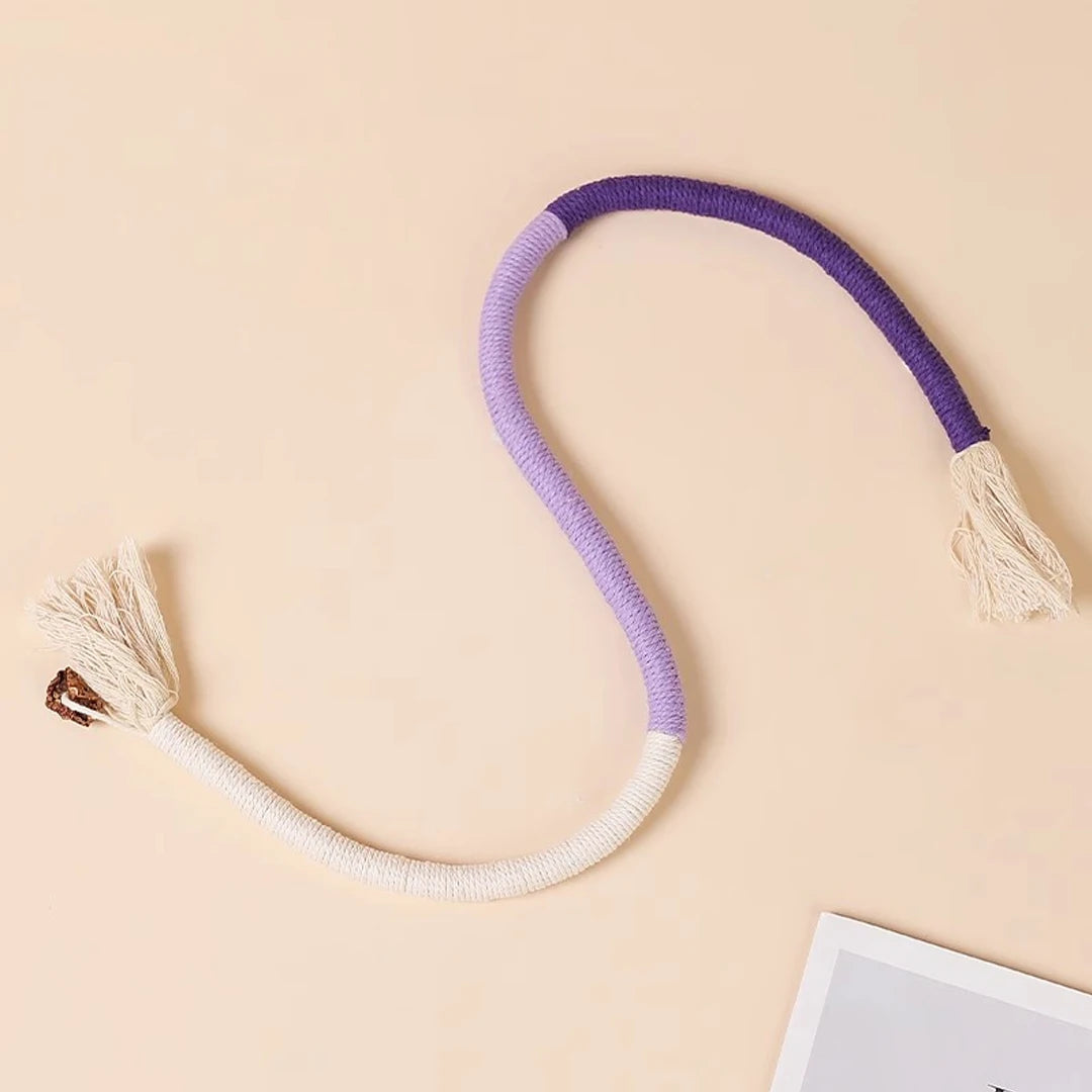 A purple and white cotton rope cat toy with tassels is shown against a light background.