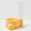 A yellow automatic pet water dispenser with a clear measuring tube is shown on a white surface.