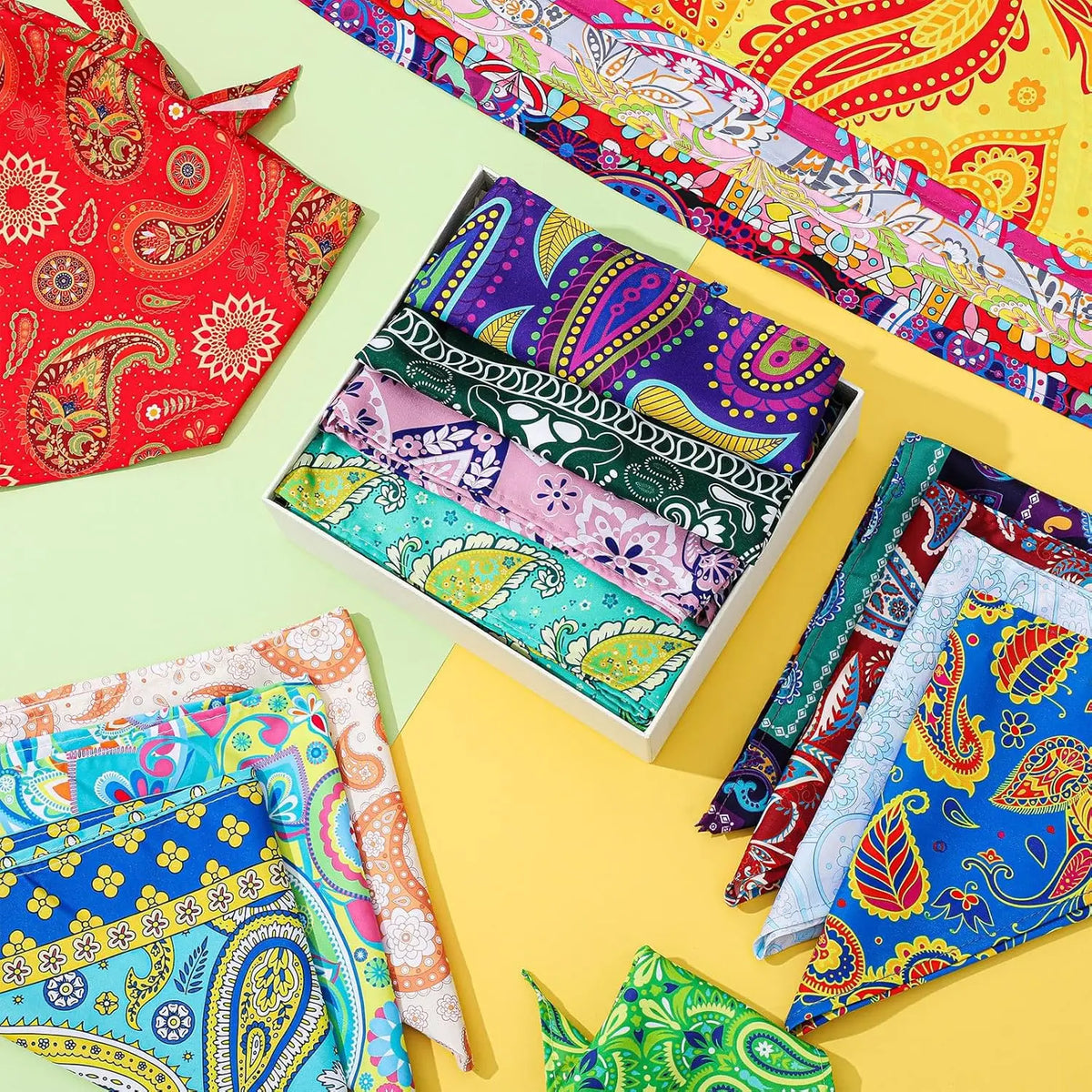 A collection of colorful paisley dog bandanas and triangle scarves are displayed on a yellow background.