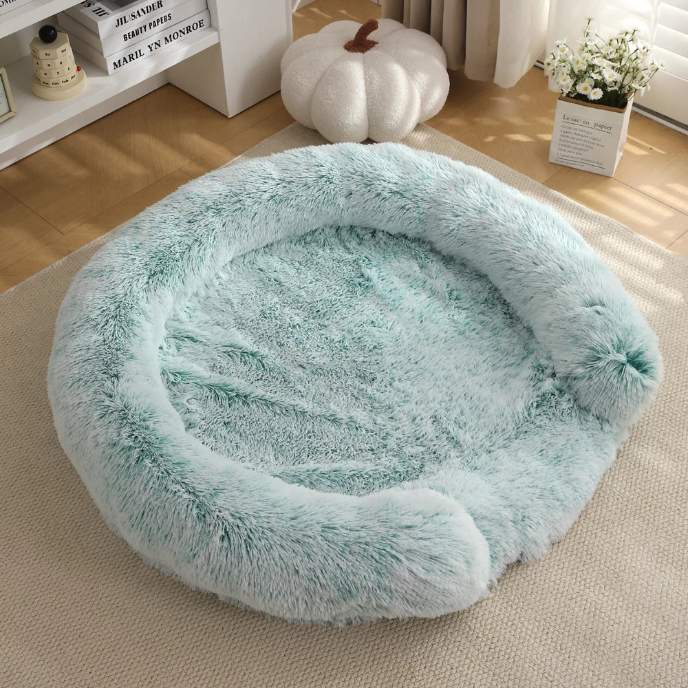 A round, fluffy, light blue dog bed resting on a cream-colored rug.