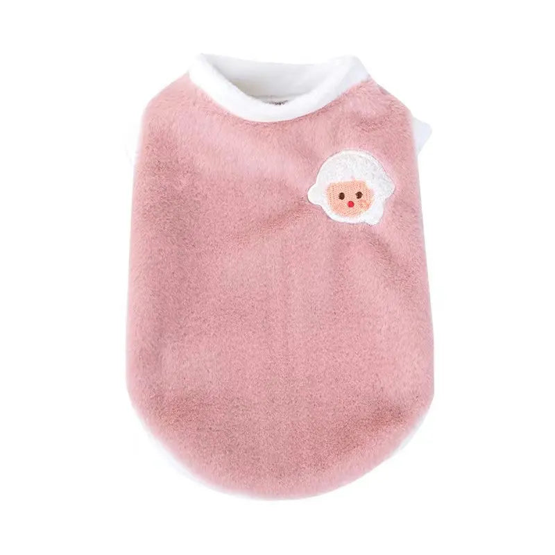 A soft pink pet vest with a white embroidered face design.