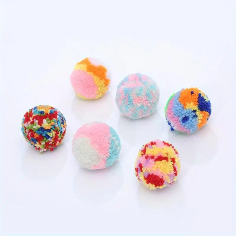 A collection of six colorful plush wool balls in various shades of pink, blue, yellow, and orange.