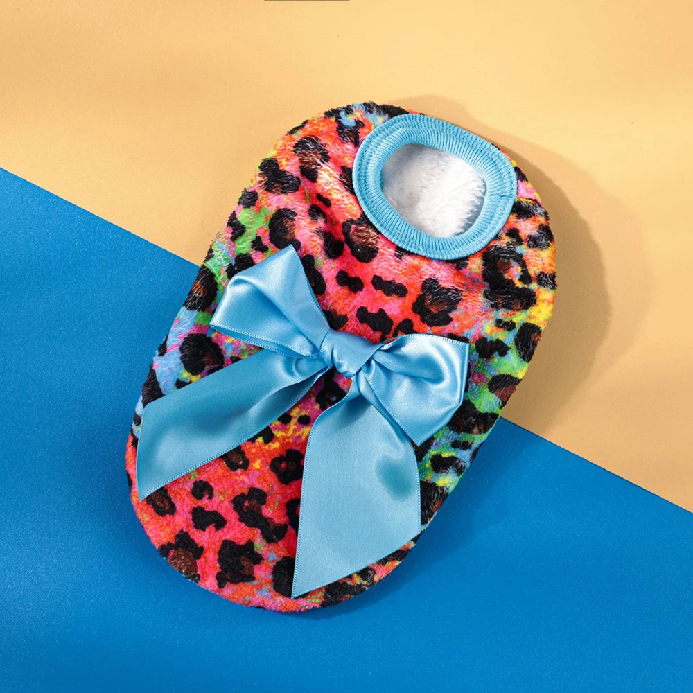 A warm knit pet sweater with a leopard print exterior and a light blue trim and bow, displayed on a blue background.