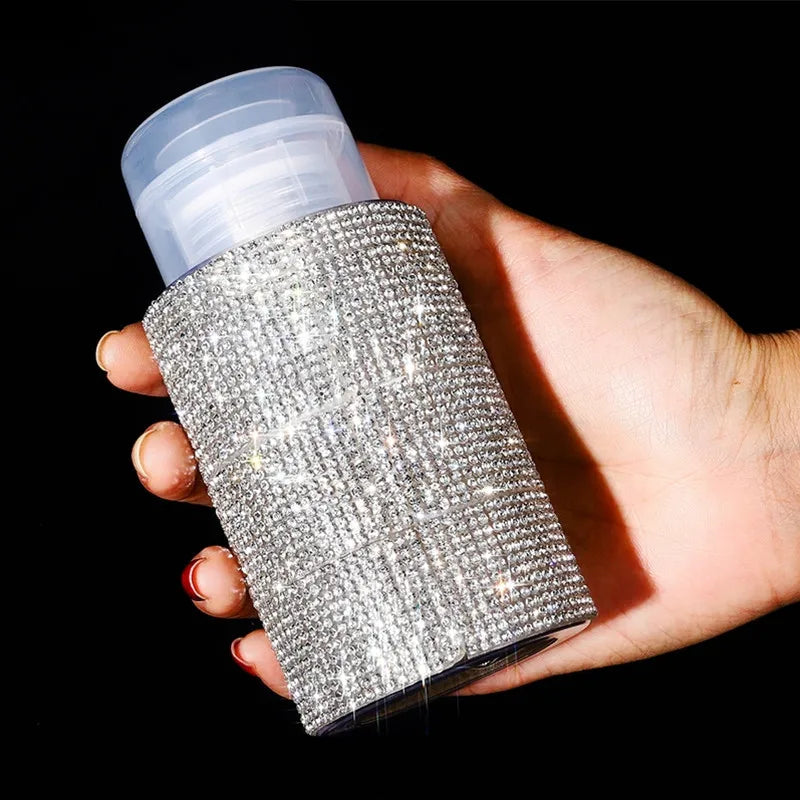 A hand holds a clear pump bottle filled with sparkling diamond design glitter for nail polish remover or makeup.