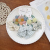 Collection de nœuds élastiques et accessoires colorés et à motifs présentés sur une assiette blanche.