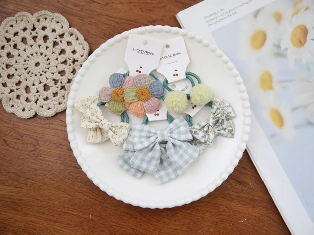 Collection de nœuds élastiques et accessoires colorés et à motifs présentés sur une assiette blanche.