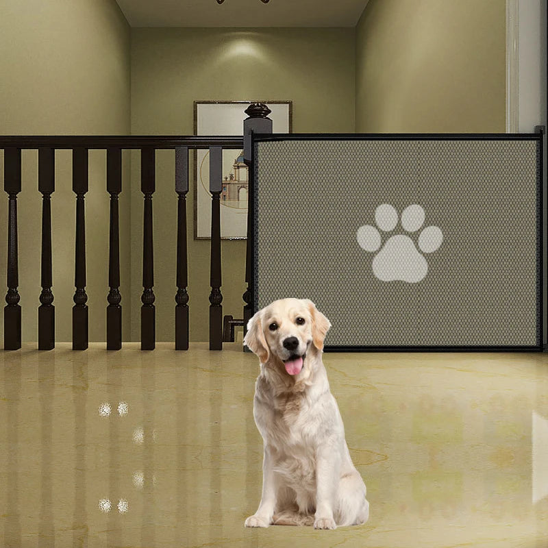 A golden retriever sits in front of a black portable folding pet safety gate with a paw print design.