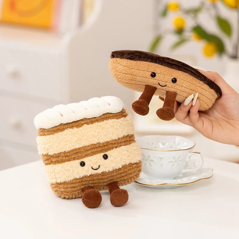 A brown and white striped dessert plush toy with small brown legs sits next to a teacup.