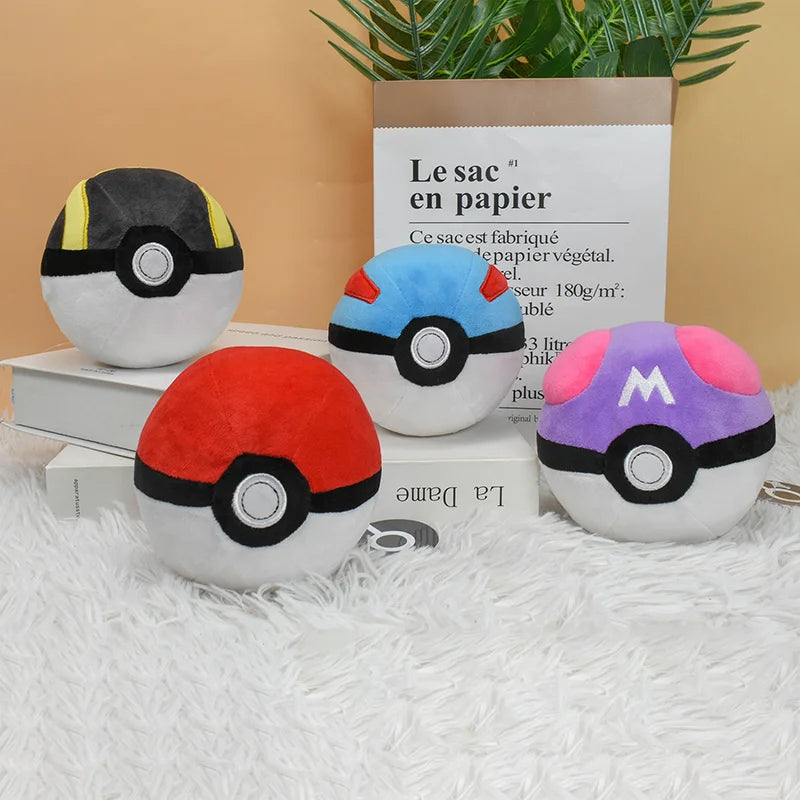 A set of three plush Poké Ball toys in red, blue, and pink colors displayed on a white surface.