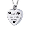 A silver stainless steel pet memorial necklace with a heart pendant engraved with the words you left paw prints on my