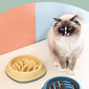 A fluffy gray cat is standing next to a yellow anti-choke slow feeding bowl for pets.