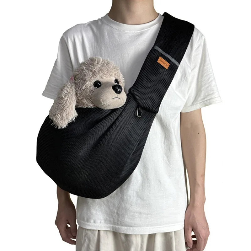 A person is wearing a black breathable mesh dog carrier crossbody bag over a white t-shirt.