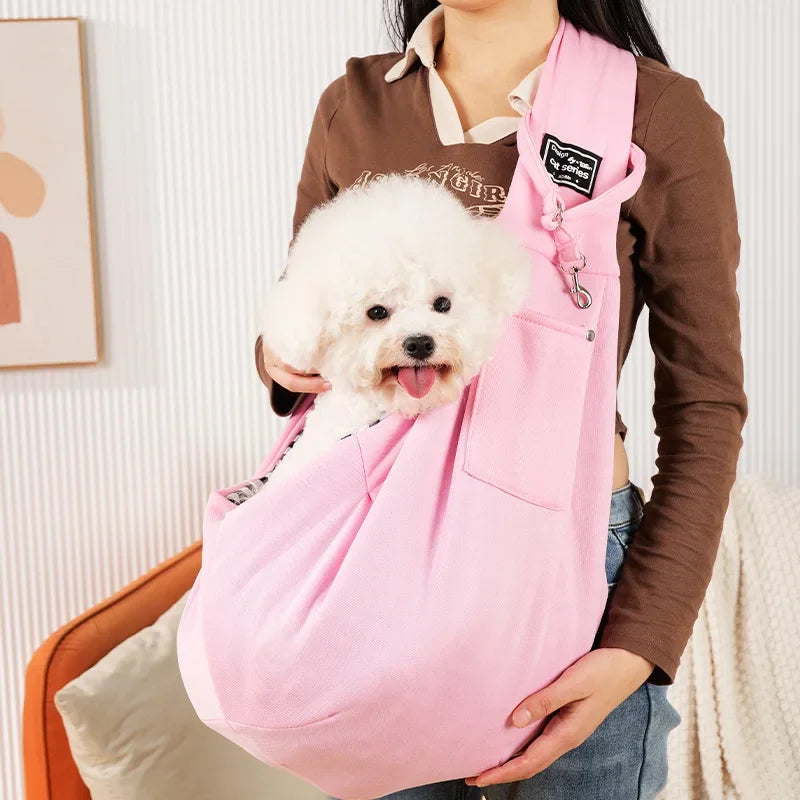 Eine Person hält einen pinken, leichten Pet-Crossbody-Sling-Tragebeutel mit einem weißen, flauschigen Hund darin.