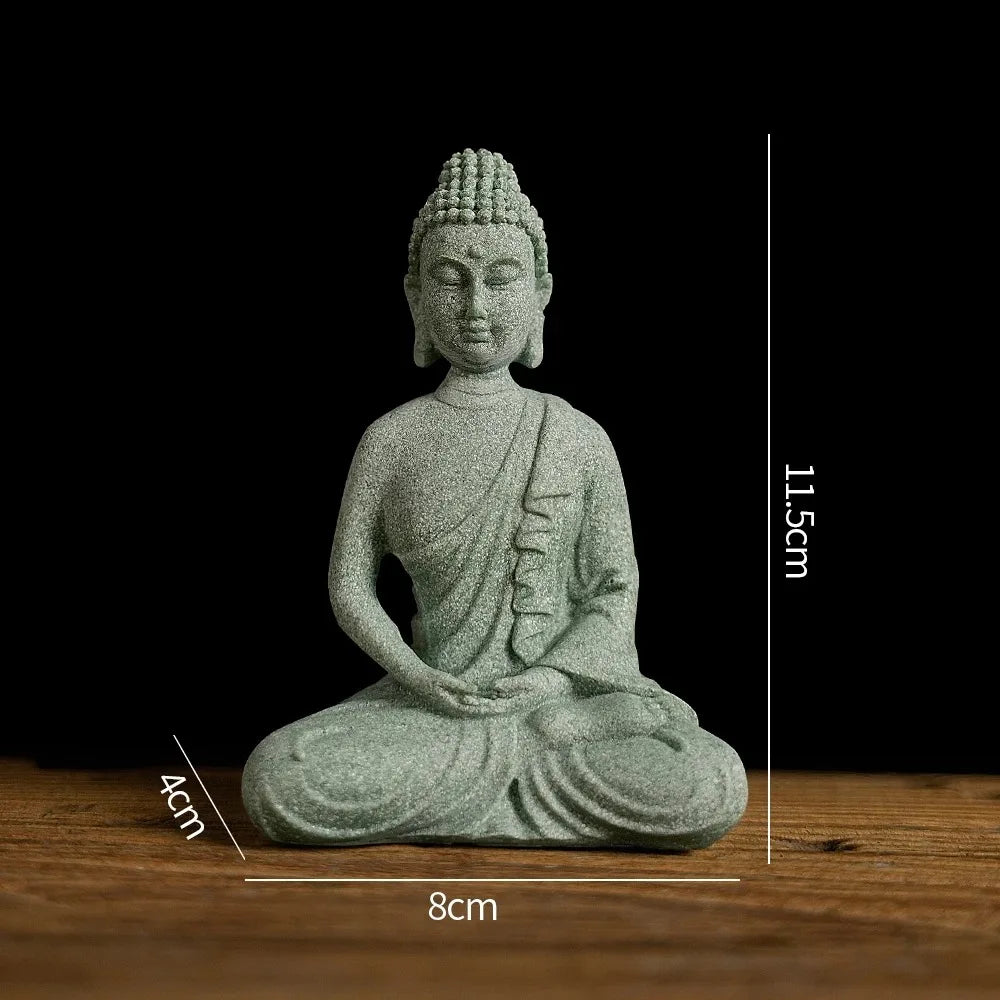 A small, grey Buddha stone statue seated in meditation pose on a wooden surface.