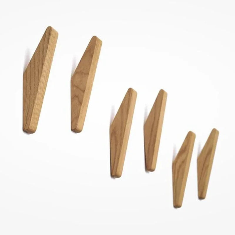 Three wooden triangle coat hooks mounted on a wall.
