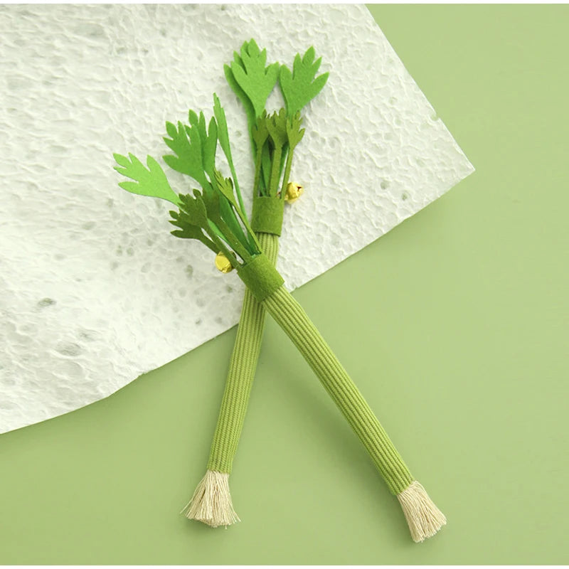 A green catnip chew stick with a squeaker is shown resting on a white cloth.
