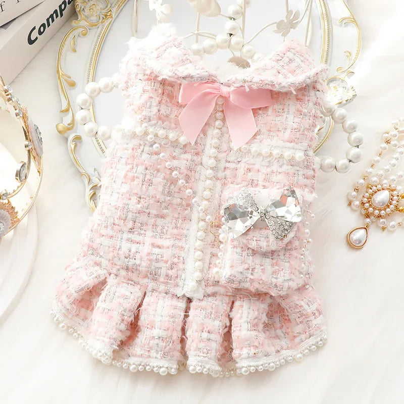 Robe pour animal de compagnie rose texturée avec bordure de perles et un nœud rose sur fond blanc.