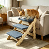 A fluffy orange and white dog is resting on a wooden pet stairs ramp indoors.