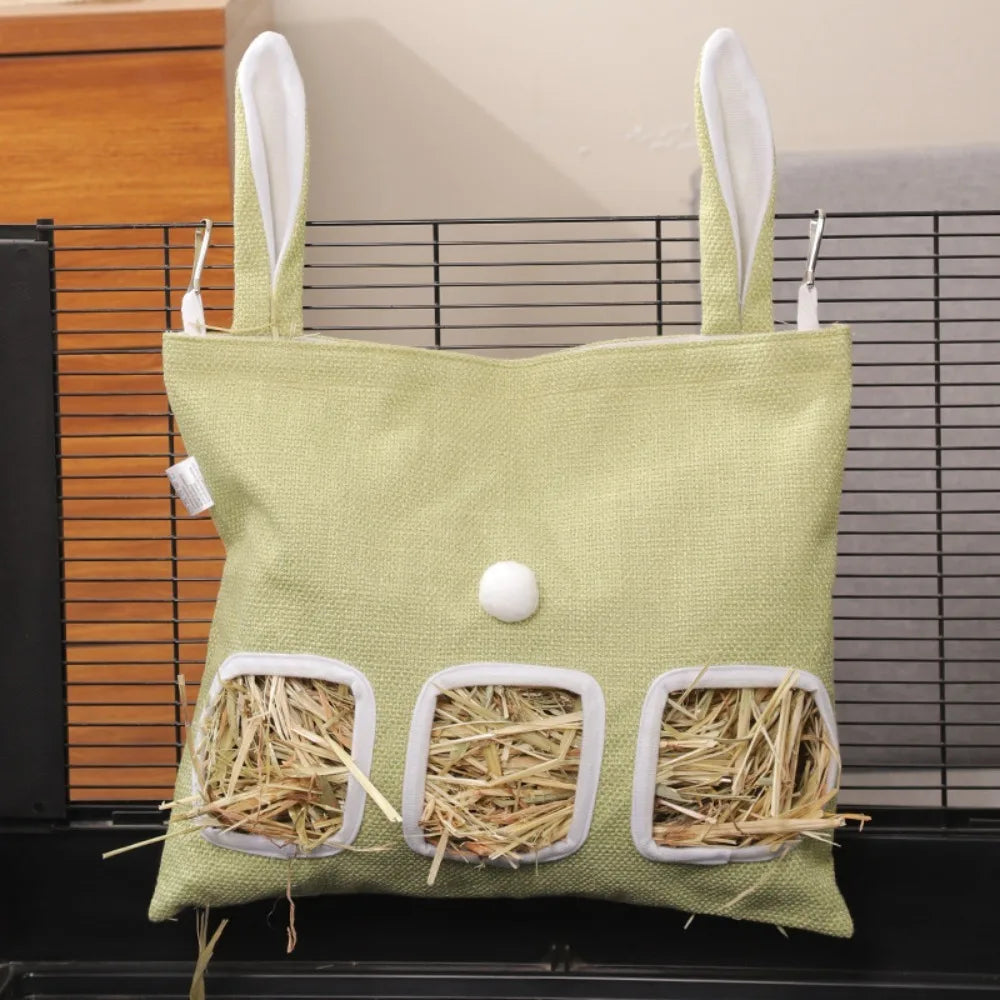 A light green fabric bag with bunny ears and multiple holes for feeding hay or straw to small animals.