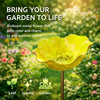 A bright yellow flower-shaped outdoor bird bath with a metal finish set in a lush garden background.