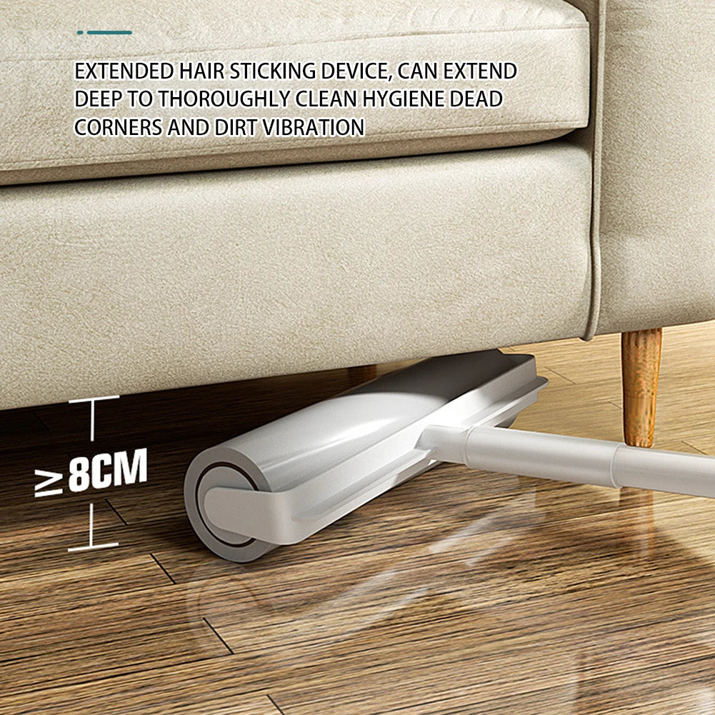 A silver lint roller with an extendable handle is shown cleaning a corner of a beige sofa on a wooden floor.