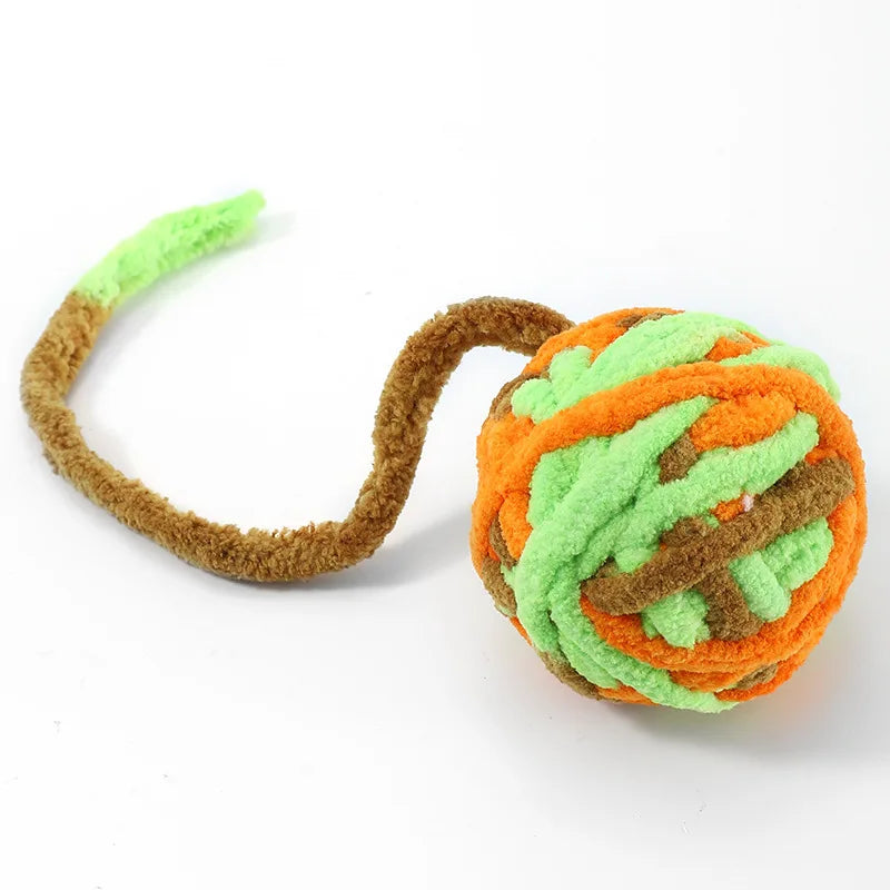 A soft plush cat toy ball with a bell, featuring bright orange and green textured fur.