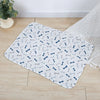 A white pet training mat patterned with blue and gray bone shapes placed on a light wooden floor.