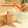 A hand is shaking an orange carrot toy to attract a cat's attention on a white surface.