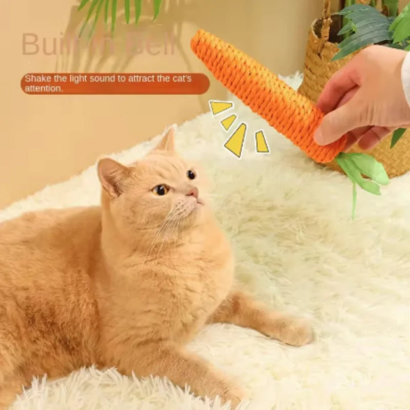 A hand is shaking an orange carrot toy to attract a cat's attention on a white surface.