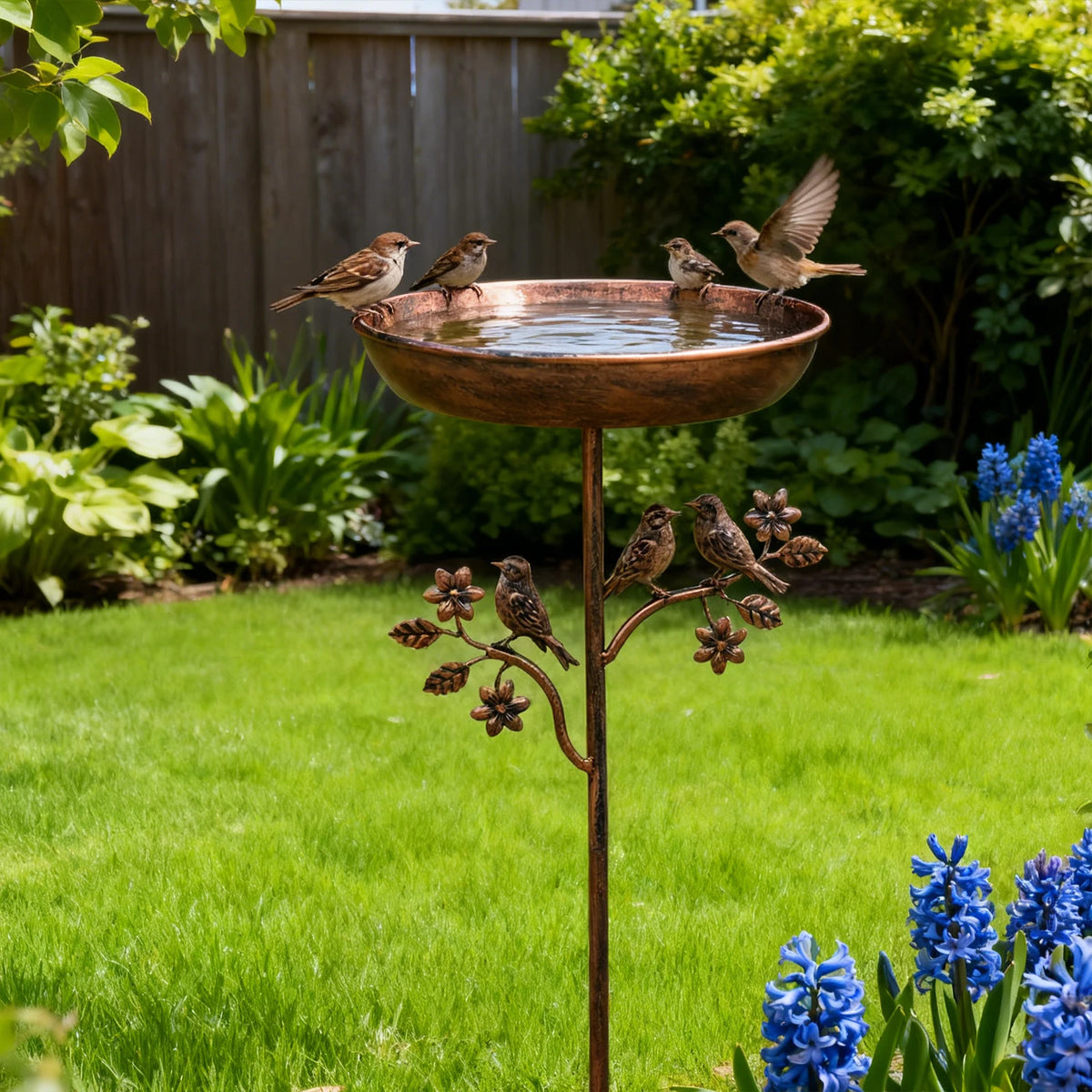Robuste Outdoor-Gießkanne aus Eisen mit kleinen Vögeln auf der Kante in einem Garten.