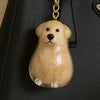 Klares, hellbraunes Hund-Anhänger-Schlüsselanhänger mit goldfarbener Kette an einer schwarzen Ledertasche.