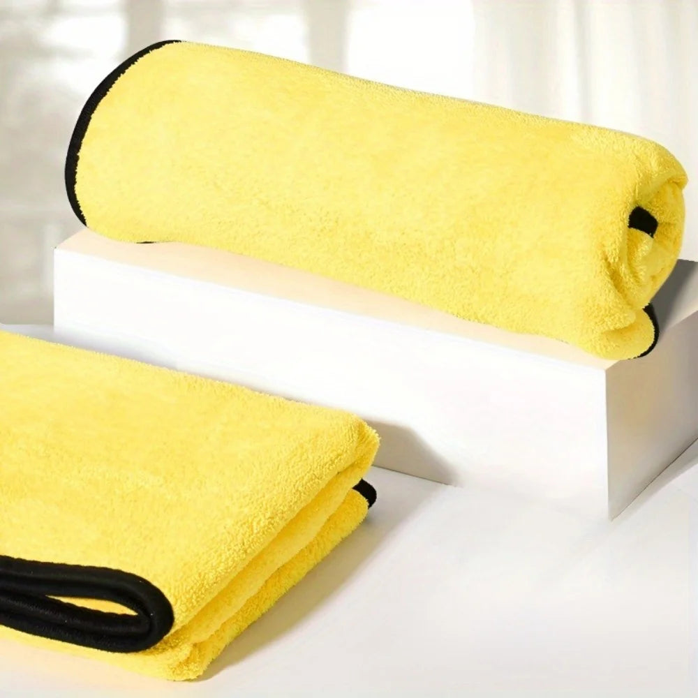 A bright yellow ultra-absorbent pet drying towel rolled on a white block and another folded towel.